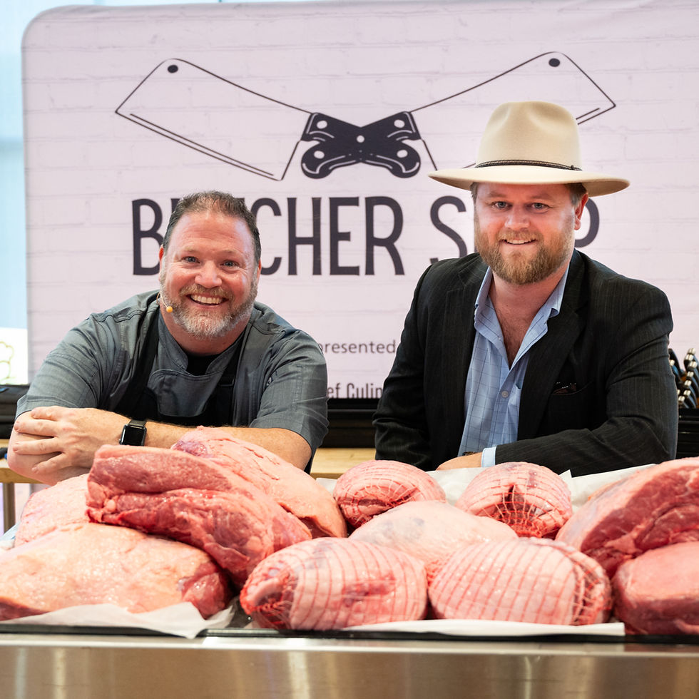 two guys leaning over a table full of australian beef and lamb