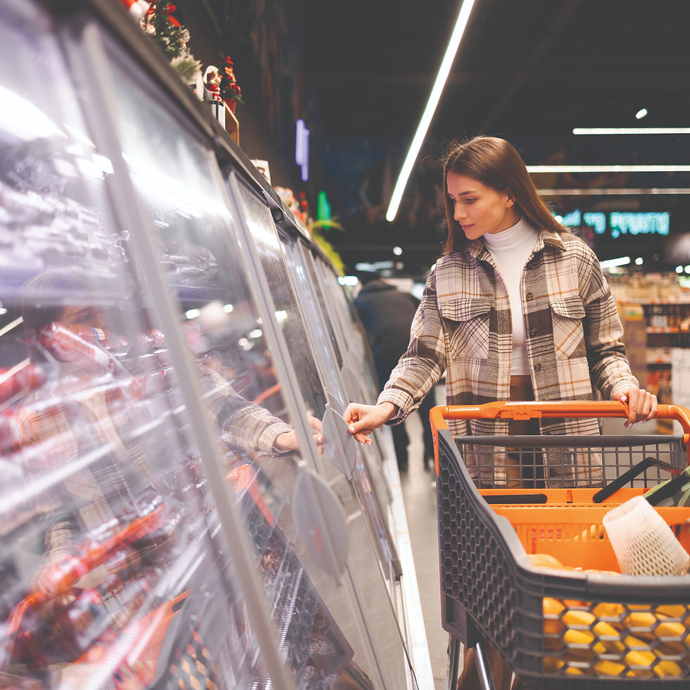 woman shopping looking at a meat case in a grocery store with her shopping cart